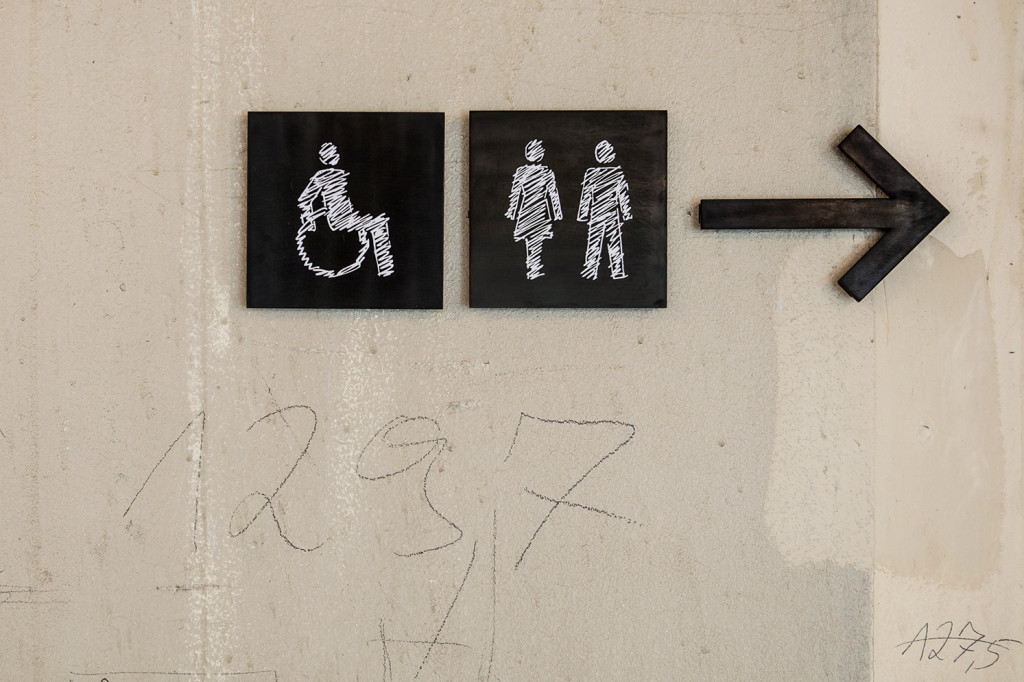 Detail der Piktogramme für Toilette auf einer grauen Betonwand mit Bleistiftmarkierungen