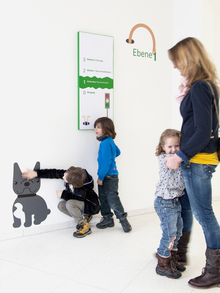 Kinder vor einer Wand mit Illustrationen und einem verspielten Orientierungssystem spielend