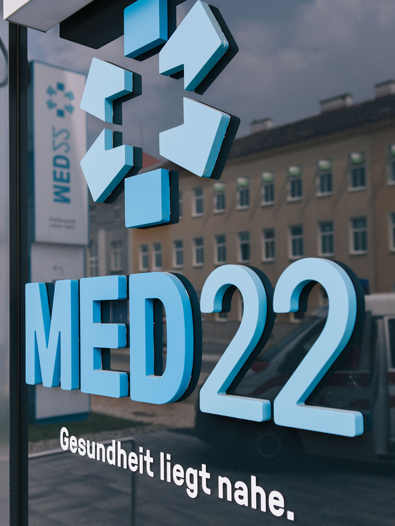 Detail of branding with logo and lettering in blue applied to glass facade