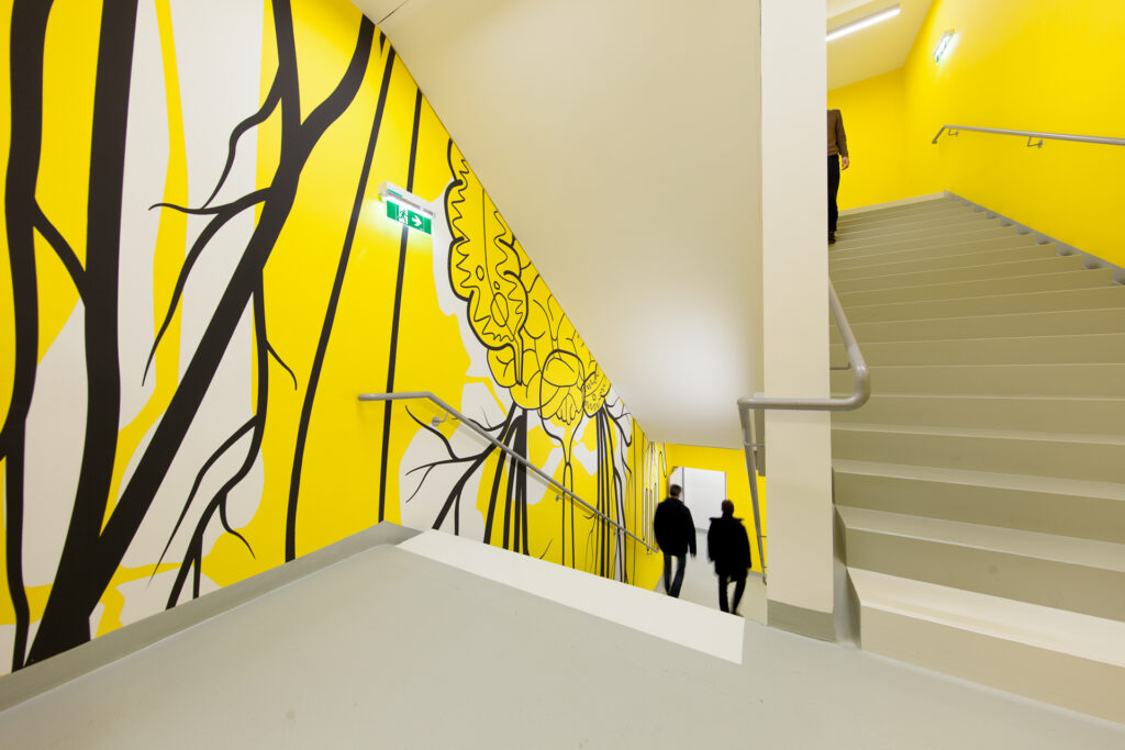 Gangbereich Stiegenhaus mit gelb-schwarzer Illustration an der Wand