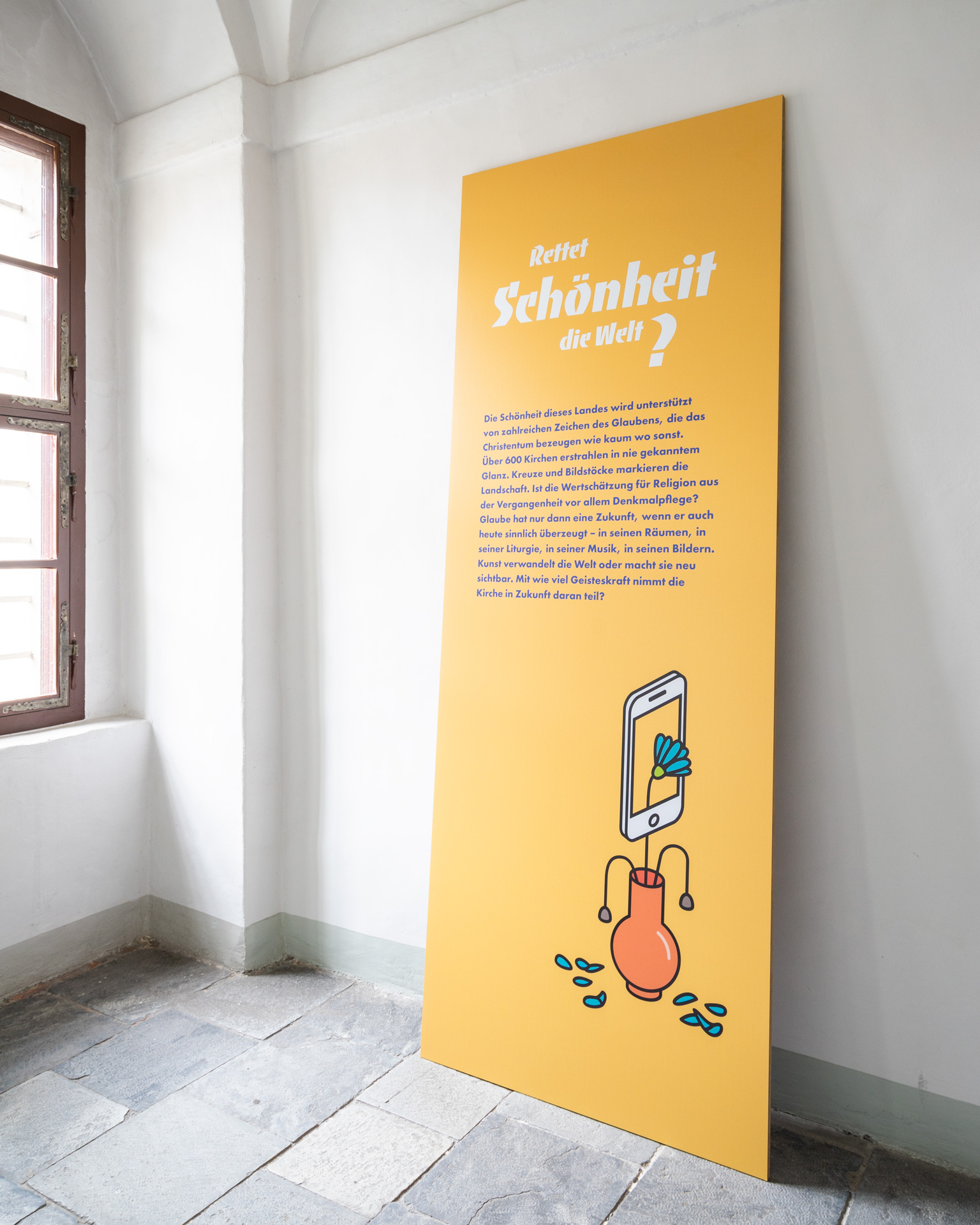 A directly printed on MDF board leaning against a wall with exhibition text and illustration on yellow background