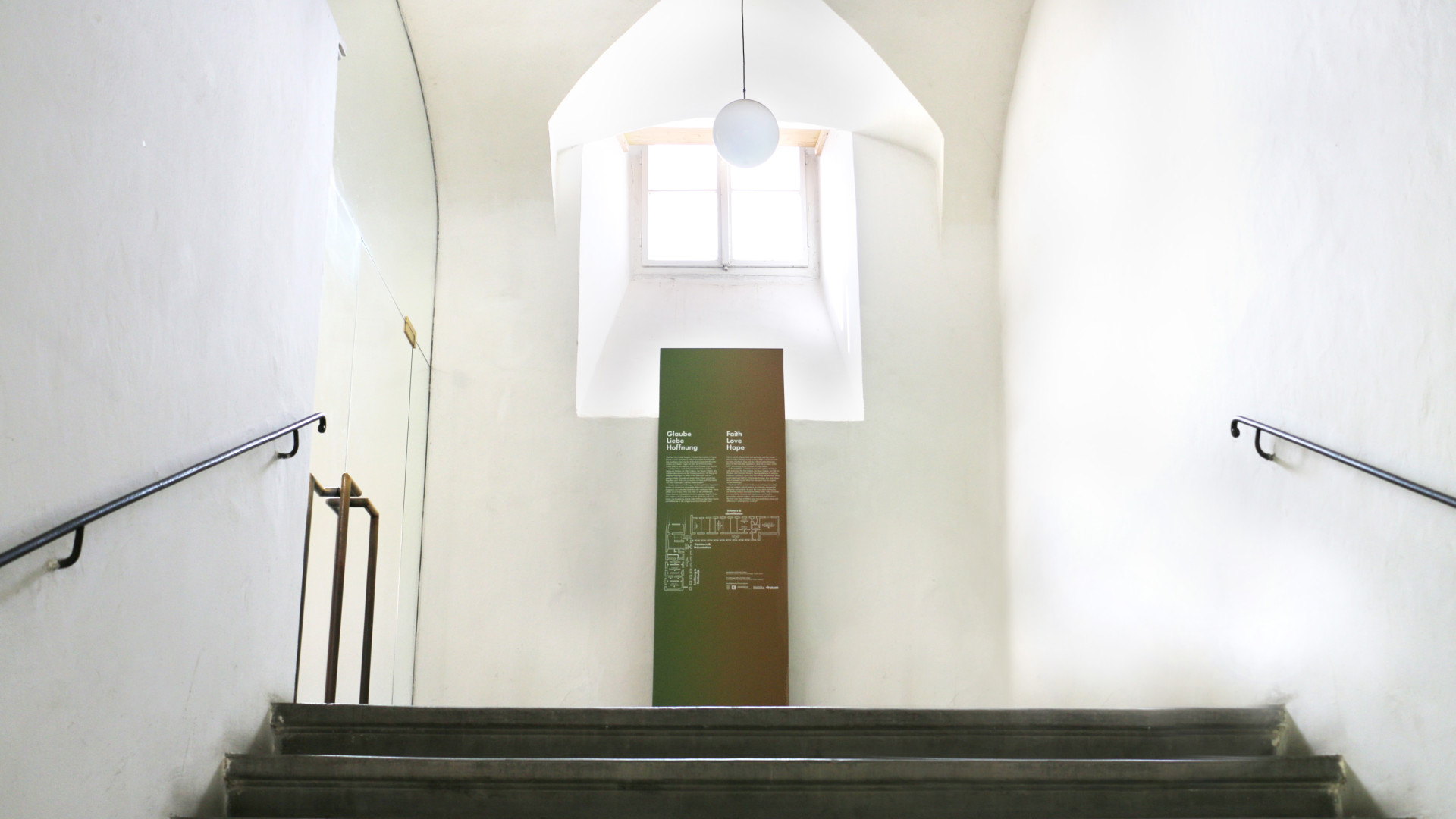 Ein Steher aus MDF Platten in einem hellen Stiegenhaus, direkt bedruckt mit Ausstellungstext