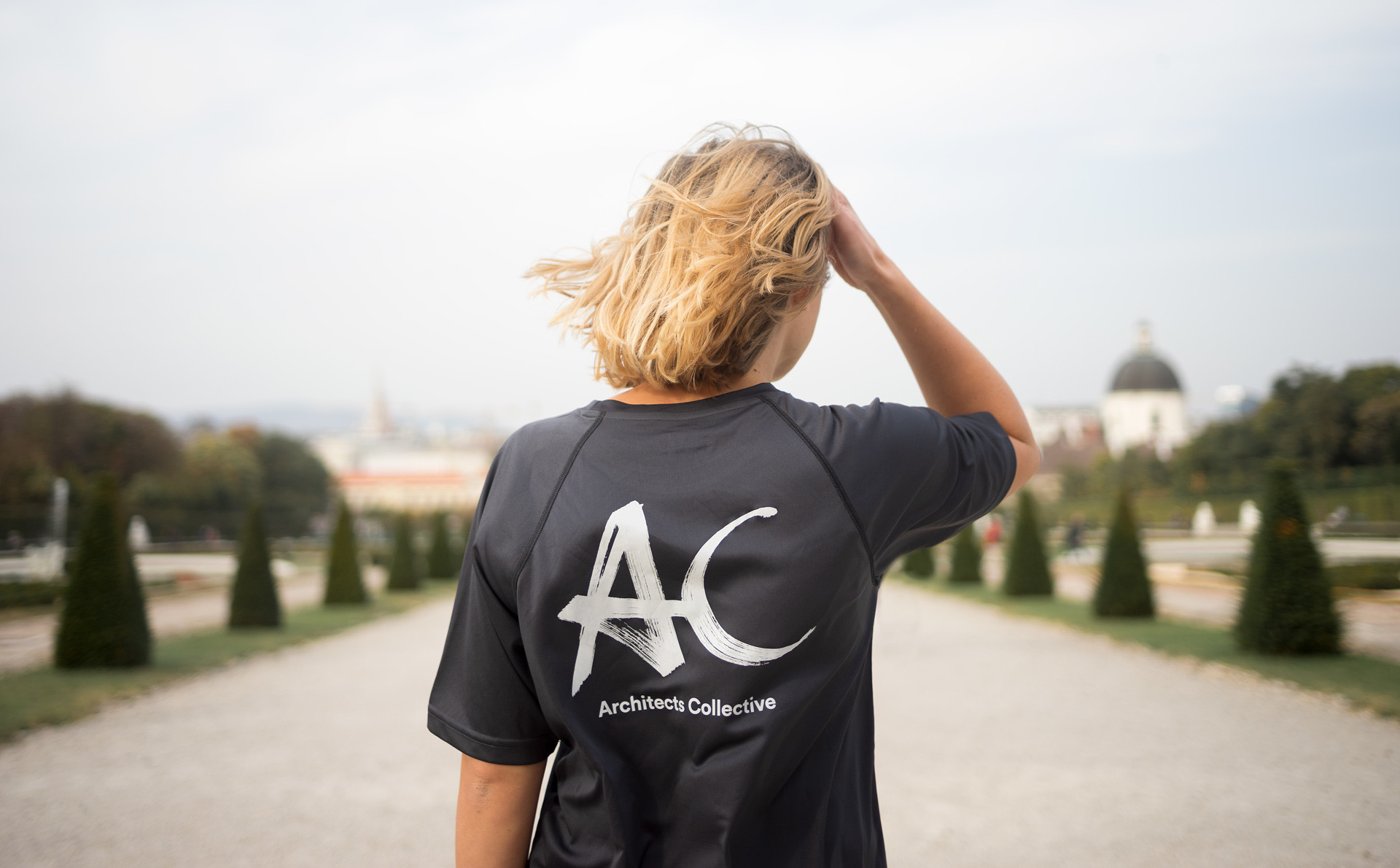 The handwritten branding of the architecture firm with the abbreviations AC in white for Architects Collective on a black T-shirt