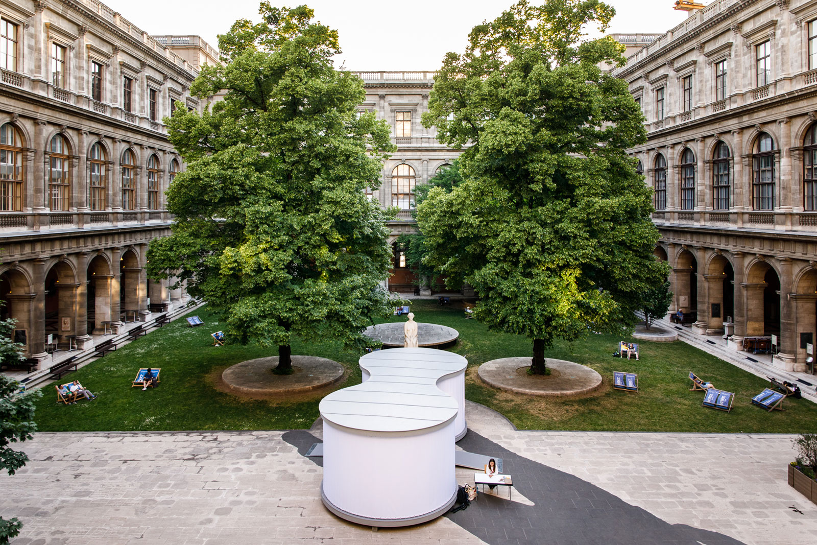 Seitliche Vogelperspektive in den Innenhof der Universität Wien mit Ausstellungspavillon, Bäumen und Gebäude