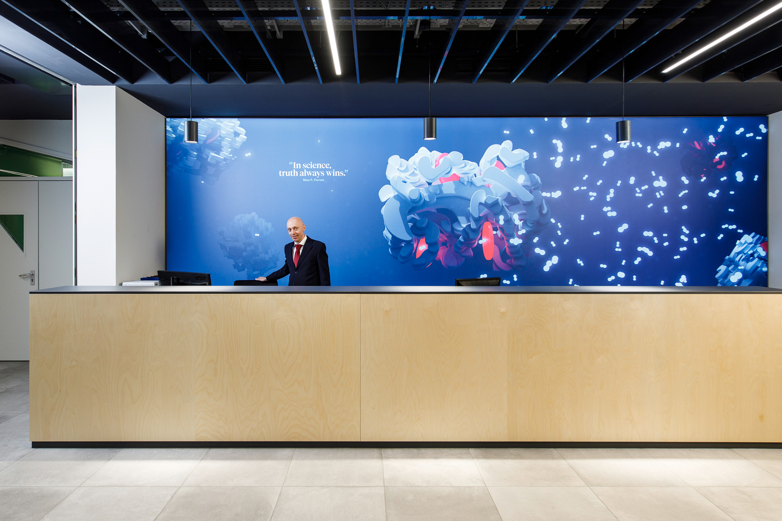 The new welcome desk with branding on the wall on the back with a man standing in front