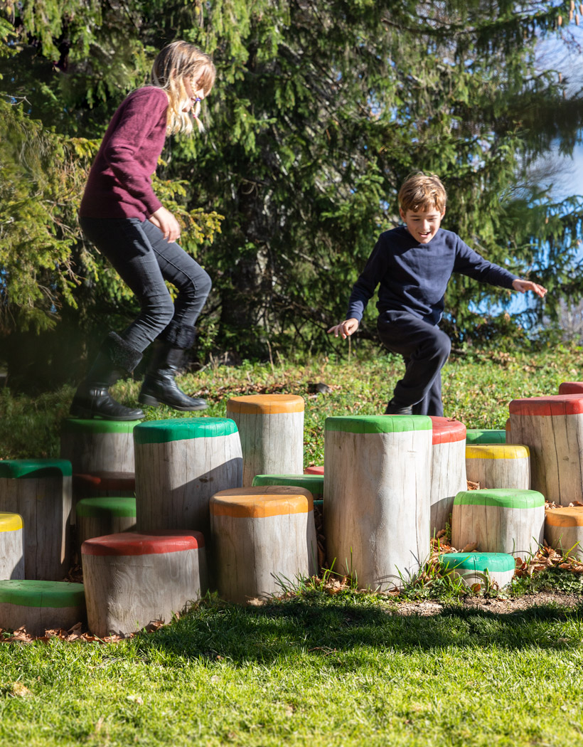 Kinder, die über Baumstämme mit farbiger Oberfläche balancieren