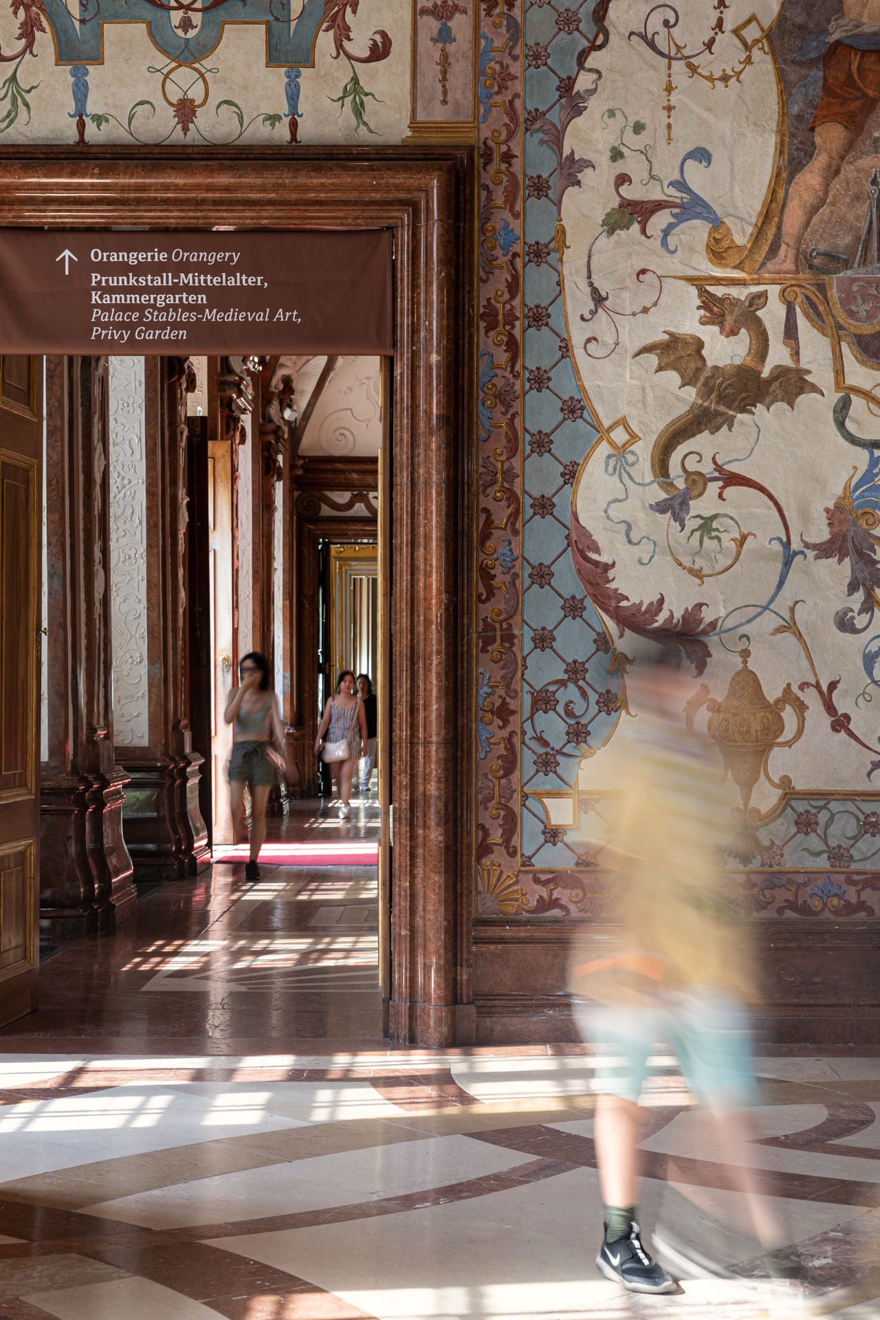 Mensch der durch die historischen Räume des Belvedere schlendert, durch einen Raum mit Wandtapete