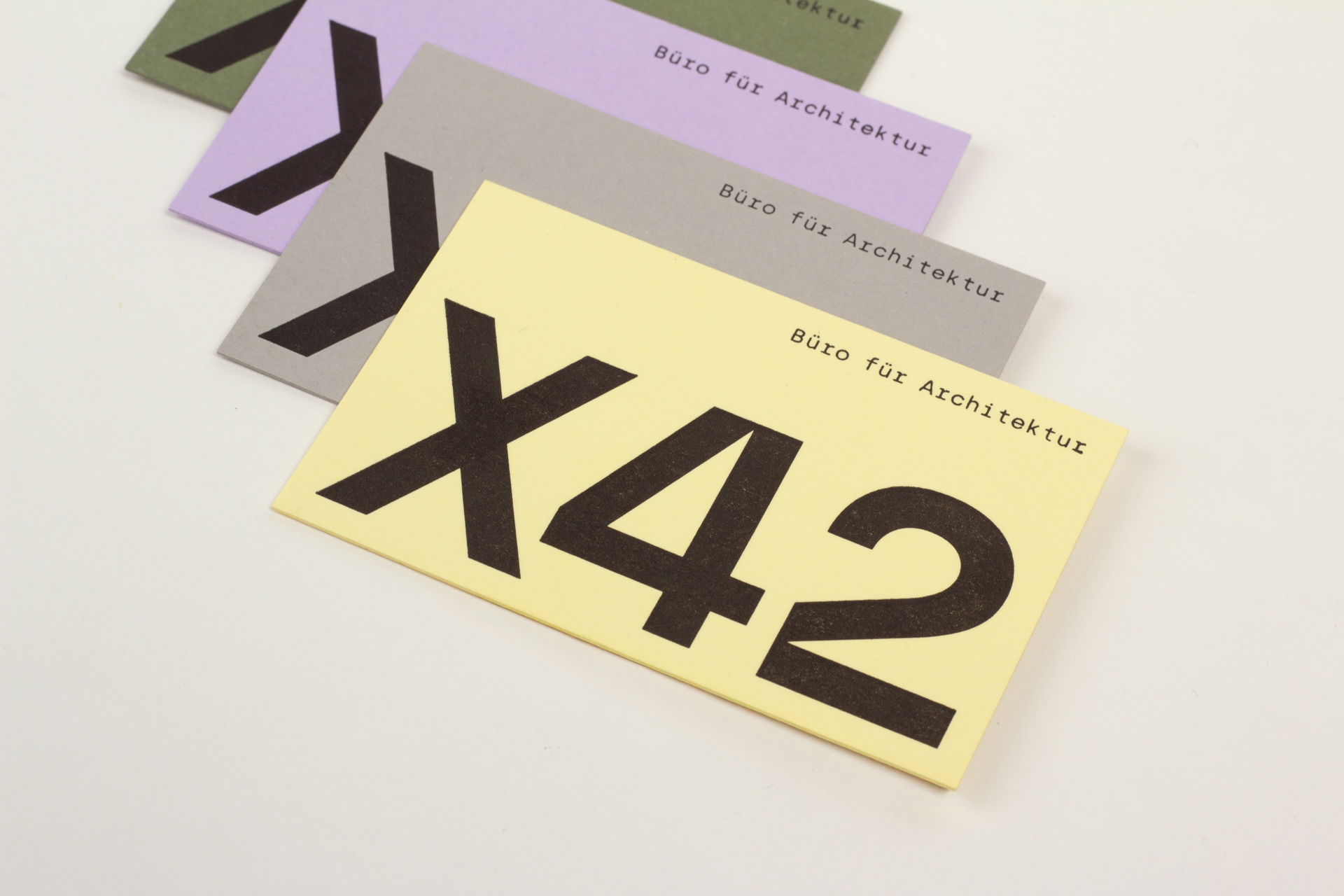 Close-up shot of the black logo X42 on stacked business cards in different colors